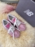 Tênis New Balance 9060 rosa com cadarços brancos ao lado de caixa preta sobre superfície macia