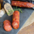 Salame pepperoni artesanal maturado em tábua preta com fatias ao lado e temperos