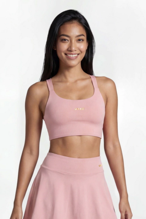 Mulher sorridente usando top básico rosa claro estilo Verano Rosê com saia combinando