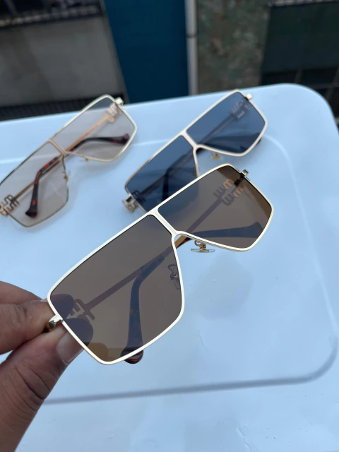 Estes óculos de sol Miu Miu, modelo SMU51ZS, apresentam uma armação metálica quadrada superdimensionada com lentes escuras e o logotipo da marca na ponte