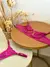 Conjunto de lingerie sensual rosa pink com detalhes em renda colocado sobre mesas redondas de madeira e vidro