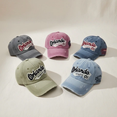 Cinco gorras bordadas en diferentes colores: gris, rosa, azul oscuro, verde y celeste, con el texto "Orlando Original 01" en el frente