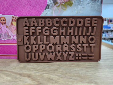 Molde de silicona para chocolate con letras del alfabeto en mayúsculas y algunos signos de puntuación, color marrón
