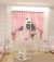 Cortina bebê rosa aberta nas laterais, confeccionada em tecido leve com bandô superior e laços decorativos. Ao fundo há uma janela iluminada, móveis brancos e elementos decorativos que compõem um quarto infantil elegante e aconchegante.cavalinho de balanç