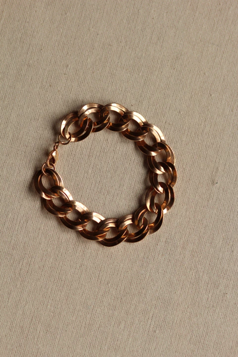 Pulseira vintage articulada, em formato de corrente, em metal com banho de ouro em tom rosé sobre tecido off-white