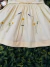 Detalhe do vestido infantil amarelo claro com bordados de flores amarelas e abelhinhas