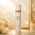 Frasco branco elegante do Body Splash Como Moiselle Isabelle La Belle 300ml com detalhes dourados em fundo dourado sofisticado