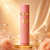 Frasco rosa do Body Splash Sabah Al Ward Sugar Isabelle da marca Decantier, em destaque com fundo dourado e rosas cor de pêssego ao redor