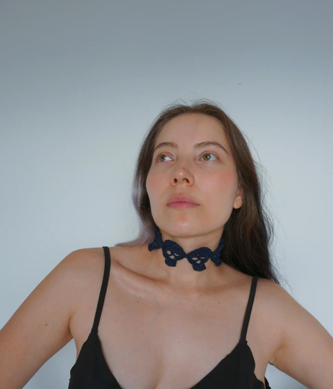 Choker Calaveras tejido a mano en hilo azul oscuro, lucido por una modelo con top negro. Amapola Amulets.