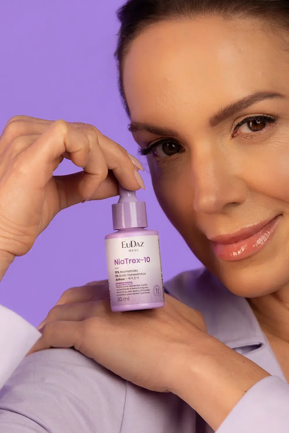 Modelo segurando o frasco do sérum facial NiaTrex-10 da EuDaz em frente ao rosto