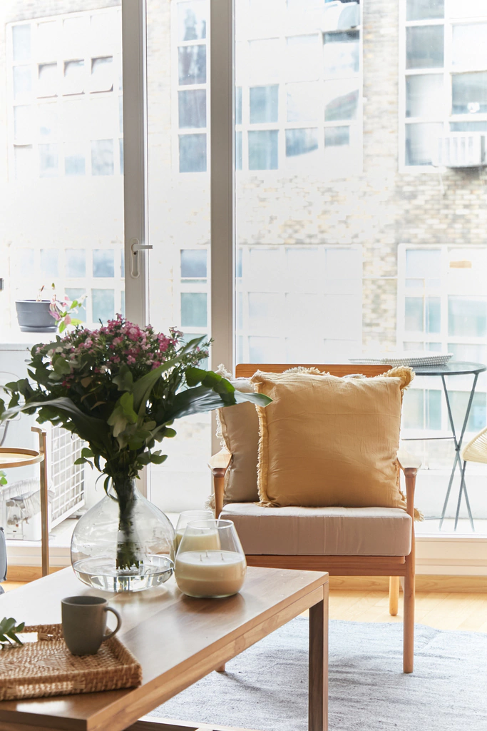 Detalle del Sillón Caitlyn mostrando su estructura de madera natural y tapizado en tonos claros