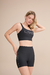 Mulher usando Top Academia Live! Icon Termocromo Noir Black, com estampa LIVE! e short fitness preto com detalhes na lateral