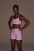 Modelo usando conjunto rosa de shorts fit Live! rosa dazzle e top  fit Live! rosa dazzle com tecido refletivo, ideal para atividades físicas noturnas.