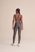 Modelo feminina usando legging fusô Allure® Adaptiv em tom escuro, vista de costas, com detalhes de alças cruzadas na blusa.