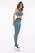 Mulher usando legging fitness verde azulado com detalhes pretos e top esportivo