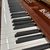 Teclas do piano digital Harmonia HS 1000, com acabamento em verniz e detalhes em preto e branco.