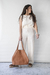 Mujer de pie con un bolso Cookies color suela, vistiendo un conjunto claro y sandalias
