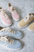 Zapatillas en tonos vainilla, celeste y rosa sobre una superficie clara.