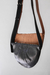 Bandolera de cuero en colores negro y suela, con diseño moderno y tirantes ajustables.