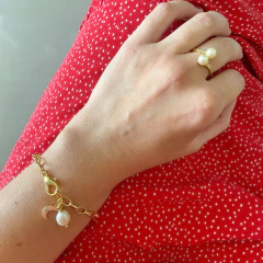 detalhe na modelo de combinação da pulseira semijoia energética banhada a ouro com pingente de Lua e pérola para trabalhar a intuição feminina