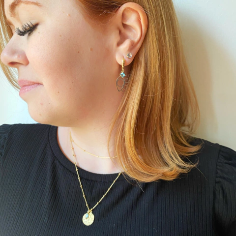 detalhe na modelo do brinco semijoia de argola com pingente olho grego e pedra turquesa banhado a ouro 18k