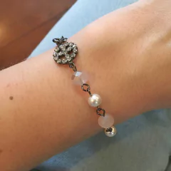 detalhe no pulso da pulseira semijoia com bolas pérola e cristal rosê, pingente paz e amor , banhada a ródio negro