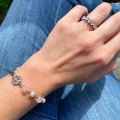 detalhe no pulso da combinação com a pulseira semijoia com bolas pérola e cristal rosê, pingente paz e amor , banhada a ródio negro