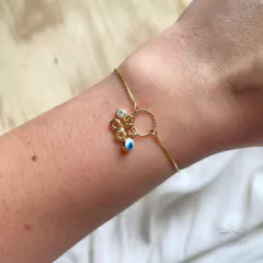 detalhe no pulso da pulseira semijoia ajustável com pingente infinito, olho grego e coração banhada a ouro 18k