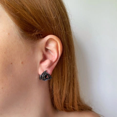 detalhe na modelo do brinco semijoia curvo de pedras pretas banhado a ródio negro