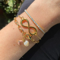 detalhe na modelo de combinação da pulseira semijoia energética banhada a ouro com pingente de Lua e pérola para trabalhar a intuição feminina