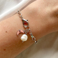 detalhe no pulso da pulseira semijoia energética banhada a ródio com pingente de Lua esmaltada em cor salmão e pérola para trabalhar a intuição feminina