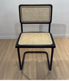 Silla Cesca negra con base y estructura metálica negra y asiento y respaldo de mimbre natural