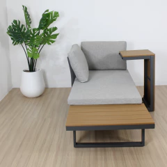 Set Cuba sillón exterior en forma de L con estructura metálica gris, superficie de madera y cojines grises, ubicado en un ambiente interior con planta decorativa