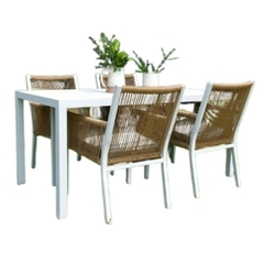 Mesa de comedor blanca con cuatro sillones de aluminio y cuerda, decorada con plantas.