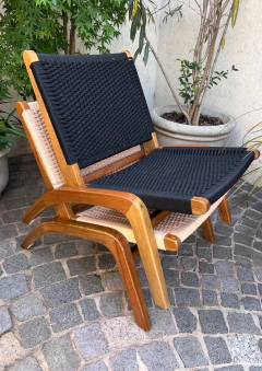 Poltrona negra de exterior sin apoyabrazos con estructura de madera clara y tejido negro.