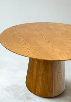 Mesa Gotta 120 de madera con superficie redonda y base cilíndrica.