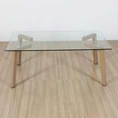 Mesa ratona rectangular con tapa de vidrio transparente y patas de madera clara sobre piso de madera