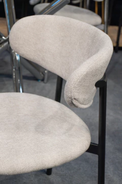 Silla tapizada color offwhite con base negra de diseño moderno en un ambiente de showroom