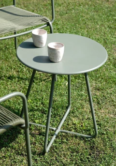 Conjunto de muebles de exterior Collins con dos sillas y una mesa redonda verde en un jardín.