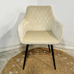 Sillón Dinamo en pana beige con base negra, tapizado con diseño de rombos, sobre alfombra de yute.