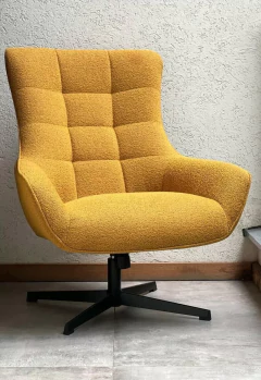 Sillón moderno de color amarillo mostaza con base giratoria negra, tapizado texturizado y diseño acogedor.