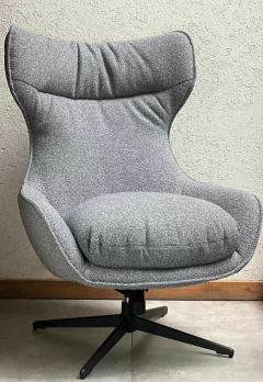 Sillón moderno con tapizado gris y base giratoria negra.