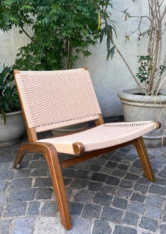 Poltrona Carl Hansen sin apoyabrazos de exterior, con estructura de madera natural y asiento tejido en color claro.