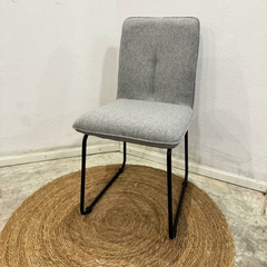 Silla Cori tapizada en chenille gris con estructura metálica negra, ideal para ambientes modernos.