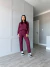 Modelo usando um conjunto moletinho na cor vinho, composto por blusa de manga longa e calça, em um ambiente interno moderno.