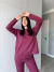 Modelo usando um conjunto moletinho vinho, composto por blusa de manga longa e calça, em um ambiente interno.