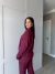 Mulher vestindo conjunto moletinho vinho com calça e blusa de manga longa em ambiente interno
