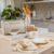 Porta pão metálico branco com a palavra "BREAD" em dourado em bancada de cozinha moderna com decoração e utensílios