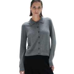 Modelo usando una camisa breve gris con botones y cuello, combinada con una falda negra.