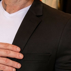 Detalle del traje tropical slim fit negro con una camiseta blanca debajo, mostrando el solapa y el bolsillo del saco.